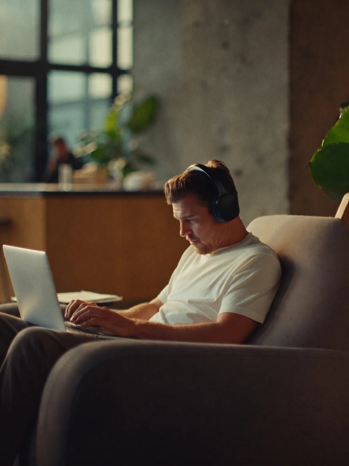 Man with headphones working in an armchair in a sunlit coworking space