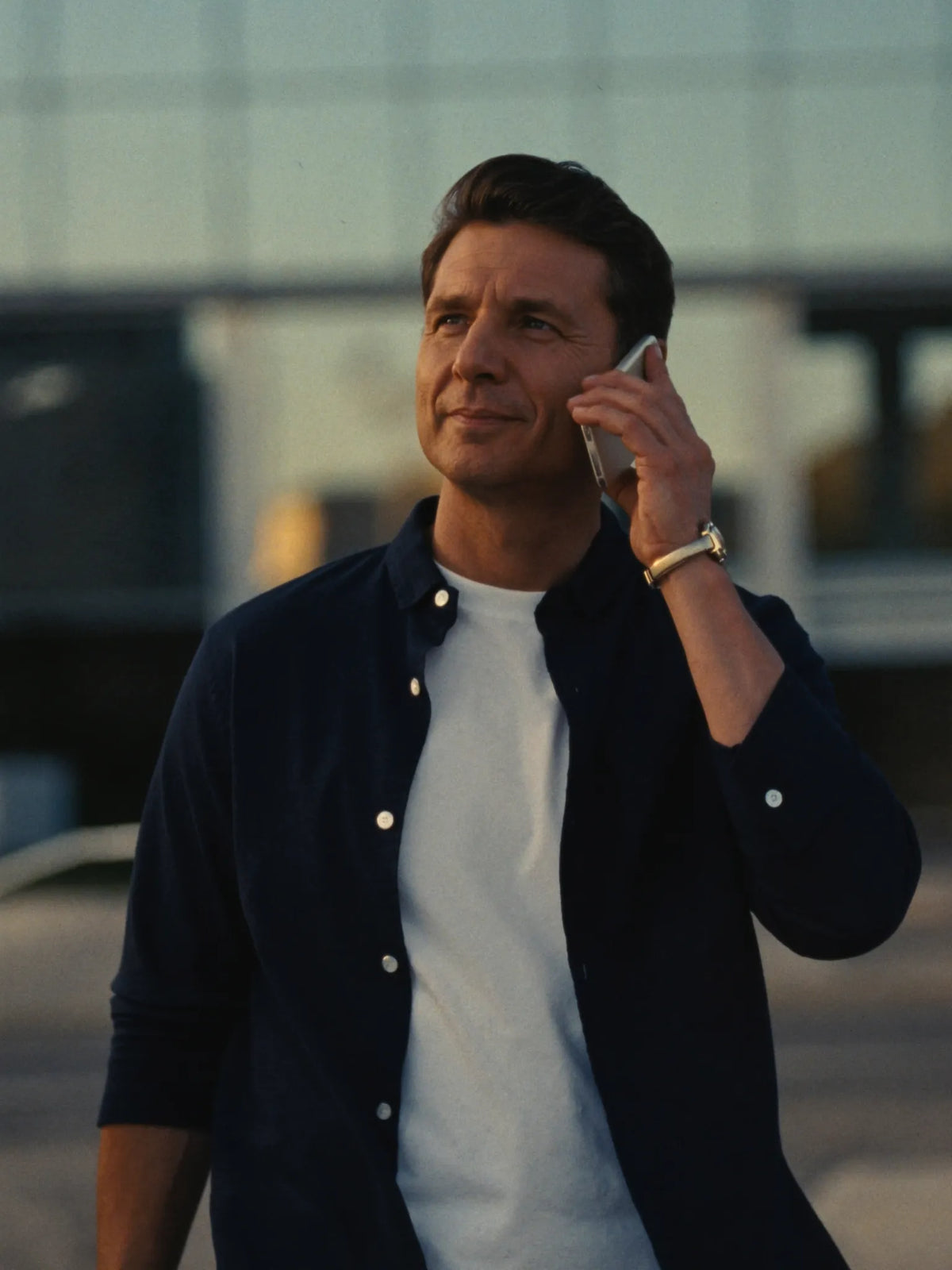 Man on a phone call outside an office building at golden hour