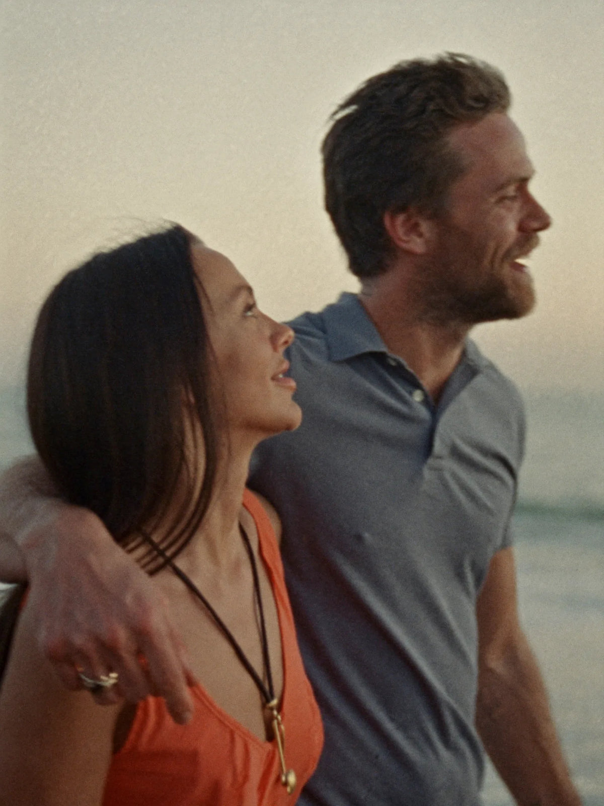Couple walking along a beach at sunset, laughing